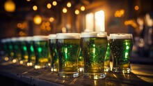 Group Of Pint Glasses With Green Beer On Wooden Table With Defocused Pub Background For St. Patrick's Day.