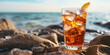 refreshing glass of iced tea rests on smooth stones at a sunny beach, waves lapping in the background