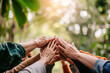 © apratim - A diverse group of hands coming together in unity, signifying teamwork and collaboration outdoors.