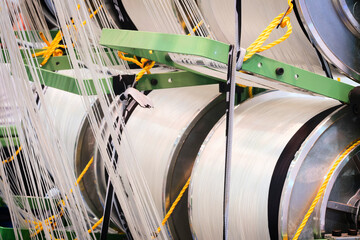 Aufkleber - synthetic textile thread,  thread at industrial weaving manufacturing machine,  textile fabric production industrial concept background