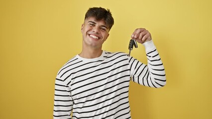 Canvas Print - Confident young hispanic man, smiling with all teeth, gleaming with joy and positivity, holding car key. happy portrait isolated on yellow background, radiates healthy, cheerful attitude.