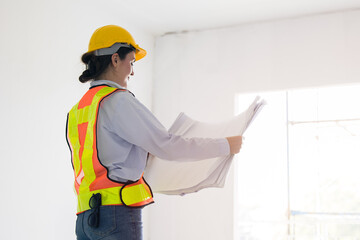 Smart young working women construction engineer builder caucasian female architect looking floor plan in under construction site building project management.