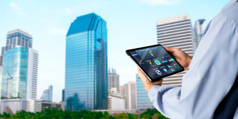 Smart Building management system(BMS) concept.Engineer Hands using digital tablet with Building Management Software on blurred modern office building as background