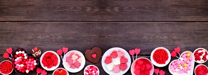 Poster - Valentines Day candy bottom border with assorted sweets. Above view on a dark wood banner background with copy space.