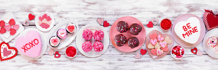 Poster - Valentines Day table scene with a variety of fun desserts and sweets. Top view on a white wood banner background. Love and hearts theme.