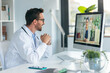 © nenetus - Mature male doctor talking in a video call with computer in the consultation.