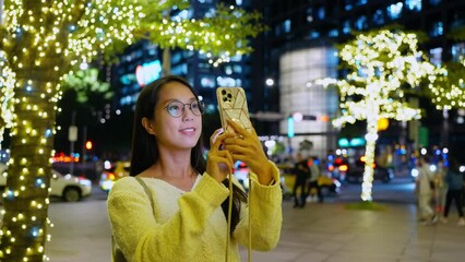 Poster - Woman use of mobile phone to take photo with the christmas decoration in the city