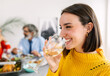 © Xavier Lorenzo - Happy young woman enjoying dinner party with family at home. Side view portrait of cheerful beautiful female toasting white wine