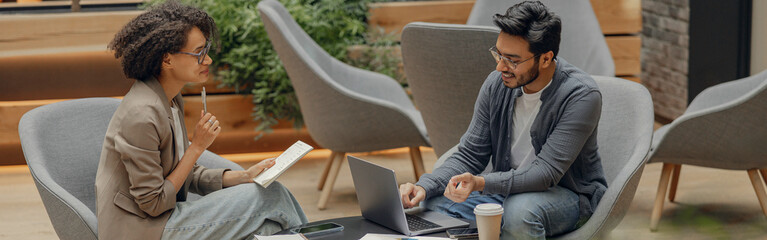 Two business colleagues working together on project while using laptop in modern coworking