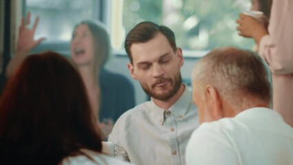 Wall Mural - Confident young male CEO businessman talks and listens to older colleague at table meeting in busy office