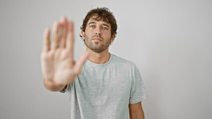 Poster - Serious young man in t-shirt gesturing 'stop' with palm of hand, stern warning expression on his face. portrait against an isolated white background.