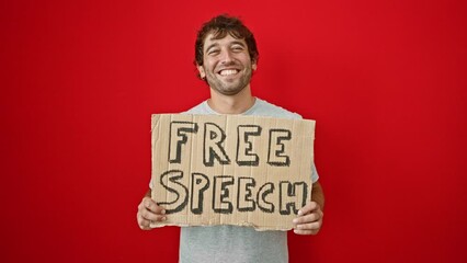 Sticker - Joyful young man, confidently flaunting his toothy smile, holds a free speech cardboard banner with positive charm. delighted and cheerful, isolated on a radiant red background.