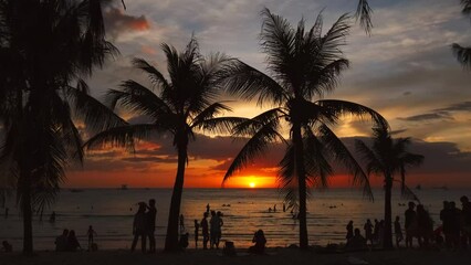 Wall Mural - Silhouetted people and palms near sea. Sunset at tropical White beach, Boracay island, Philippines, slow motion 4k