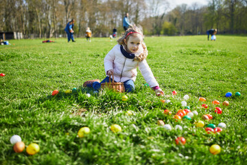Wall Mural - Adorable preschooler girl playing egg hunt on Easter