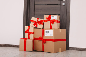 Christmas gift boxes on floor near door. Sending present by mail