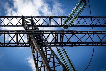 Wall Mural - Metal support of a high-voltage power line with insulators on a sunny summer day against a blue sky