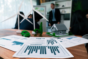 Wall Mural - Mockup electric car with eco-friendly energy infrastructure on table with blurred background of productive business team meeting to contribute natural preservation and sustainable future. Quaint