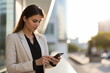 © duyina1990 - Young businesswoman using smartphone in urban setting