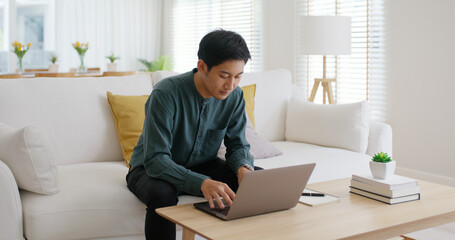 Gen Z asia people male guy relax work at home office sofa typing e-mail on digital laptop remote job online. Young adult hybrid worker man in reskill upskill career web page coding data MBA class.