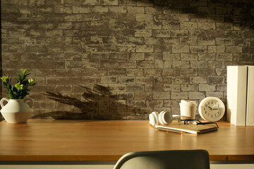 Wall Mural - Home office interior. Picture frame, coffee cup, notebook and pencil holder on white table against brick wall. Copy space.