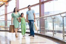 Happy Indian Family Of Three Enjoying In Shopping Mall With Paper Bags, Shopping Bags In Hands. Shopping Concept