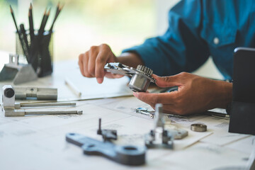 Mechanical engineer working with blueprints and using vernier caliper  to measuring bearings.