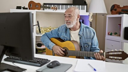 Wall Mural - Bald man with beard playing guitar in an office with musical instruments in background