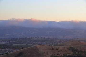 Wall Mural - The Marine layer moves in the East Bay at sunset as the hilltops and clouds lit up in a golden hue of the setting sun