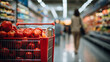 Supermarket Aisle with Red Shopping Cart, Blurred figure of a shopper walking past a shopping cart filled with fresh red tomatoes in a supermarket aisle, depicting everyday grocery shopping