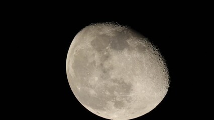 Closeup footage of the waning gibbous moon moving slowly in its orbit in the black night sky