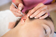 Crop chiropractor massaging ear of woman during auriculotherapy in beauty salon