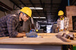 © Wanwajee - Young White man carpenter labor, craftman working in wood workshop together, looking follow by peice of work furniture industry.