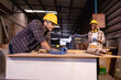 © Wanwajee - Young White and blur American Affrican men carpenter labor, craftman working in wood workshop together with happiness, furniture industry.