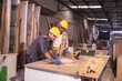 © Wanwajee - Young affrican american and white men carpenter labor, craftman working in wood workshop together, talking. Timber industry and furniture industry.