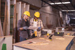 © Wanwajee - Young affrican american and white men carpenter labor, craftman working in wood workshop together. Looking paper Timber industry and furniture industry.