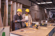 © Wanwajee - Young affrican american and white men carpenter labor, craftman working in wood workshop together, talking. Timber industry and furniture industry.