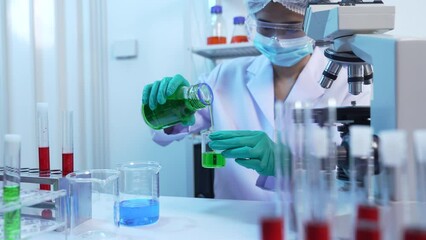 Wall Mural - Asian people scientist in lab coat and protective gloves working with test tubes with mix liquids, with microscope and other test tubes in the background in laboratory.