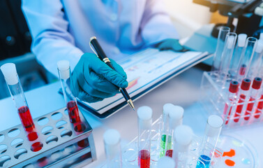 Sticker - Asian people scientist in lab coat and protective gloves working with test tubes with green and red liquids, with microscope and other test tubes in the background in laboratory.