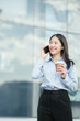 © NINENII - Businesswoman walking and talking phones on street in city Outside Office with drinking coffee.
