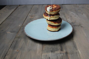 Sticker - Cottage cheese pancakes, homemade pancakes lie in a pile on a gray background with space for the text copyspace, poured with condensed cream. Traditional breakfast with cottage cheese