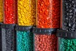 Multicolored cylindrical recycled plastic pellets arranged by color in a container.