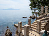 Stone steps leading into the Adriatic sea in Lungomare promenade with Cres island in the background. Lungo Mare goes from Volosko to Opatija.  Kvarner Gulf, Istria, Croatia, Europe