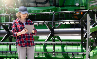 Fototapete - Woman farmer with digital tablet on a background of harvester. Smart farming concept