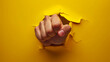 fist punching through hole in yellow paper, concept of anger, revenge, attack, power, violence and creativity