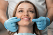 © YURIMA - A woman sits in a dental chair, happily demonstrating her bright smile, under the sensitive and attentive gaze dentist who is ready to do everything to preserve her health and the beauty her smile.
