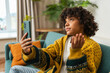 © Юлия Завалишина - African American girl holding smartphone having video chat. Female blogger chatting with best friends in social network. Young woman having virtual meeting online chat video call at home