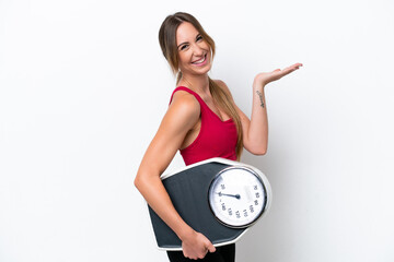 Wall Mural - Young caucasian woman isolated on white background with weighing machine