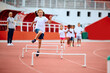 © Drazen - Happy girl jumping over obstacles while running at stadium.