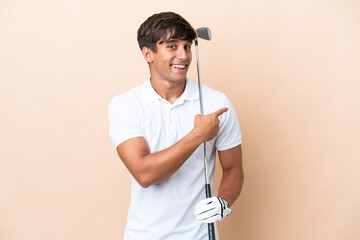 Wall Mural - Young golfer player man isolated on ocher background pointing back