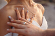 © Silviya Stoyanova - Wedding concept, couple touching their hands with wedding ring bands. Sea necklace. Loving married young couple.